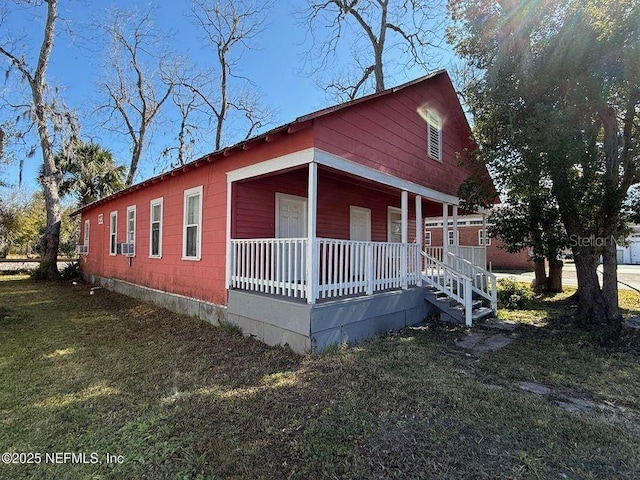 view of side of home with a lawn, cooling unit, and a porch