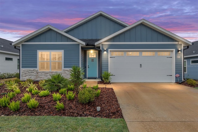 view of front of home featuring an attached garage, stone siding, board and batten siding, and concrete driveway