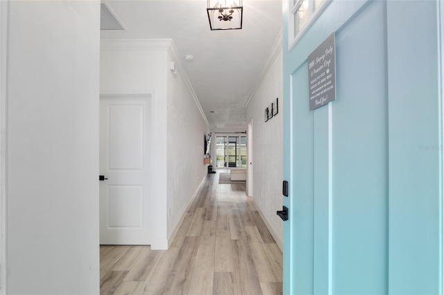 hallway with baseboards, visible vents, crown molding, and light wood finished floors