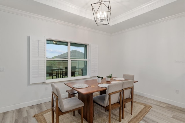 dining room with a notable chandelier, light wood finished floors, baseboards, and crown molding