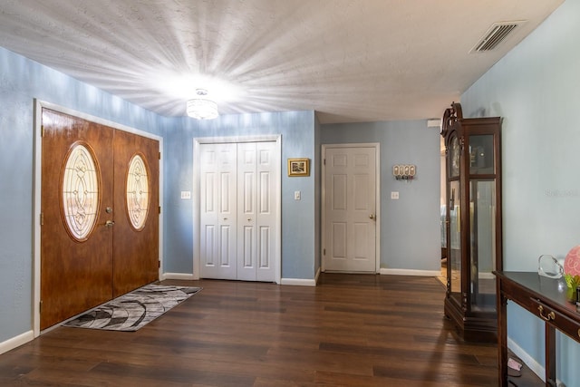 entrance foyer featuring dark wood-type flooring, visible vents, and baseboards