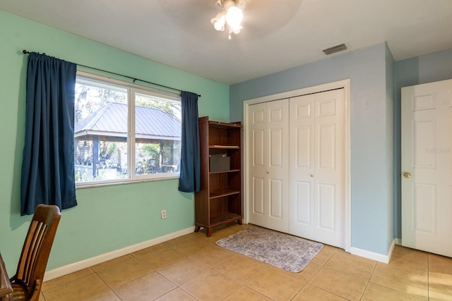 unfurnished bedroom with a closet, visible vents, baseboards, and light tile patterned floors