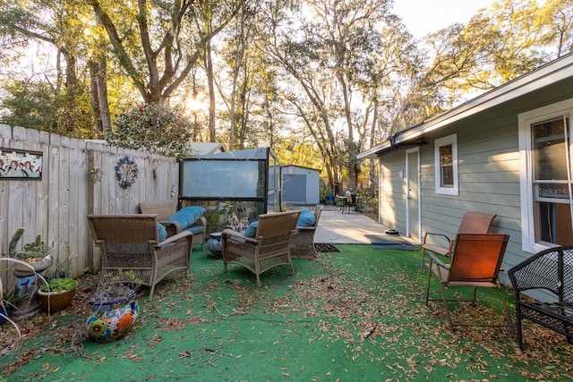 view of yard featuring an outbuilding, fence, a storage unit, a patio area, and outdoor lounge area