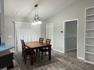 dining space with built in shelves, dark wood finished floors, vaulted ceiling, a chandelier, and baseboards