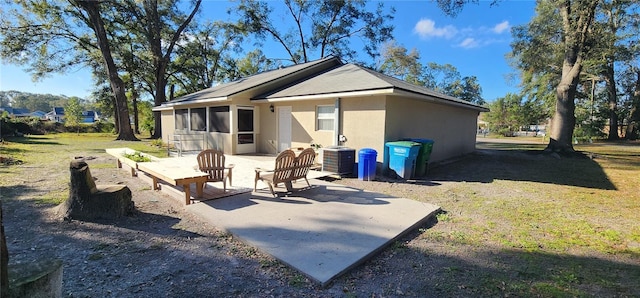 back of property with a lawn, a patio area, a sunroom, and stucco siding