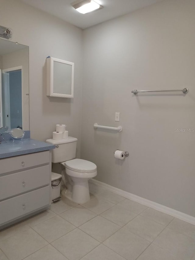 bathroom with toilet, vanity, baseboards, and tile patterned flooring