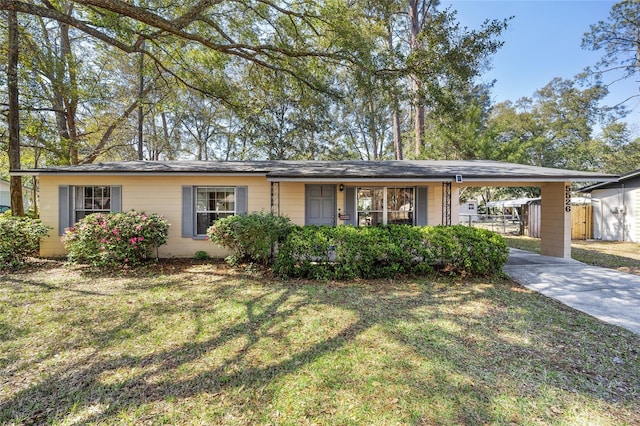 single story home featuring a carport, a front yard, concrete driveway, and fence