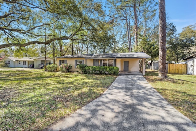 ranch-style home featuring fence, an attached carport, concrete driveway, and a front yard