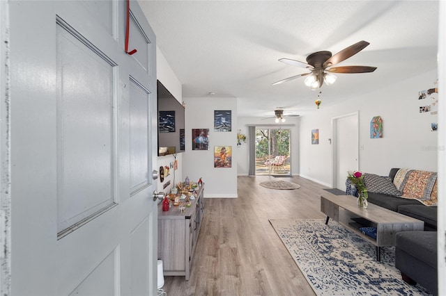 living room featuring a textured ceiling, light wood finished floors, and baseboards