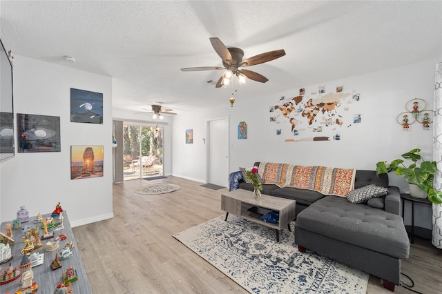 living room with a textured ceiling, light wood finished floors, a ceiling fan, and baseboards