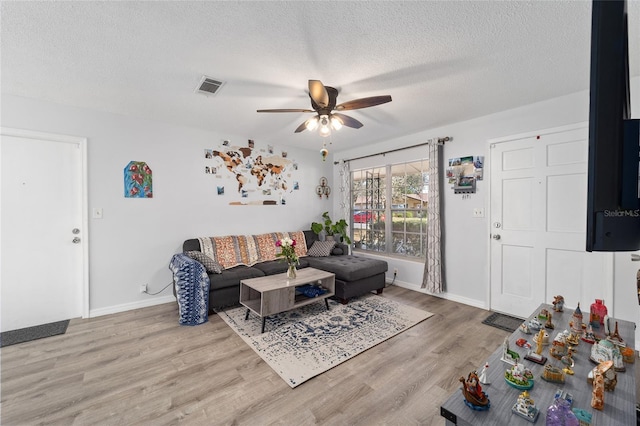 living room with visible vents, a ceiling fan, a textured ceiling, wood finished floors, and baseboards