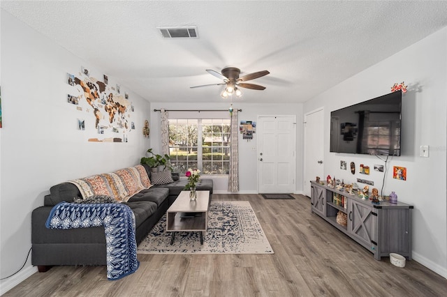 living room with visible vents, ceiling fan, a textured ceiling, and wood finished floors