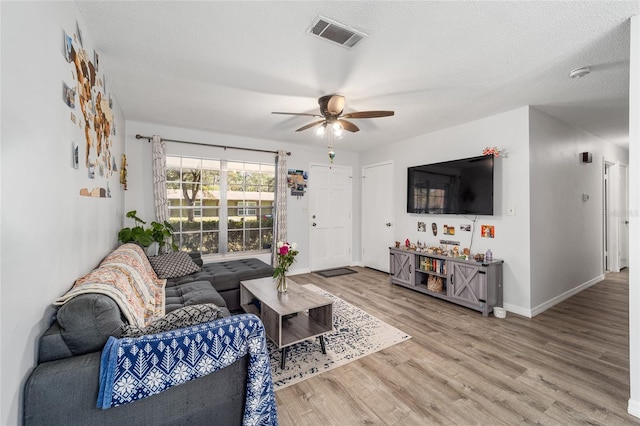 living area featuring baseboards, visible vents, ceiling fan, wood finished floors, and a textured ceiling