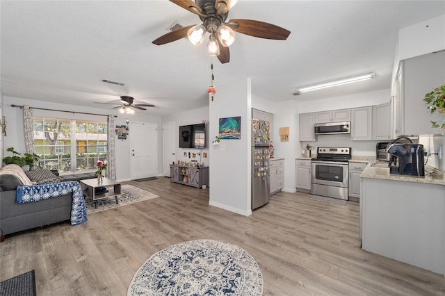 living area with baseboards, a textured ceiling, visible vents, and light wood-style floors