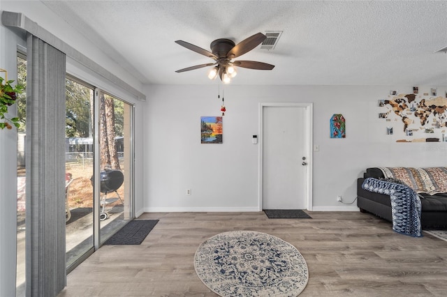 interior space featuring visible vents, baseboards, ceiling fan, wood finished floors, and a textured ceiling