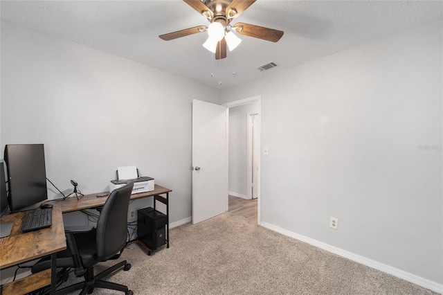 office area with a ceiling fan, light carpet, visible vents, and baseboards