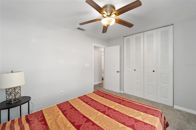 carpeted bedroom featuring a ceiling fan, a closet, visible vents, and a textured ceiling