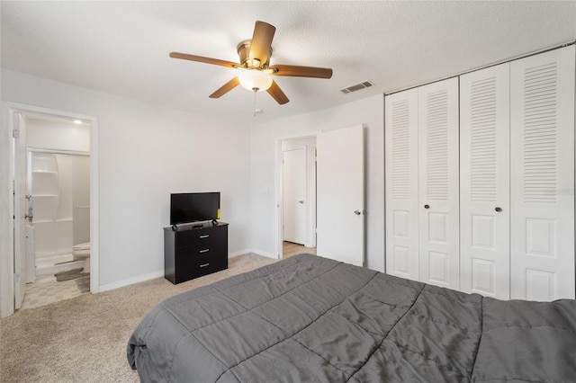 carpeted bedroom featuring a textured ceiling, connected bathroom, visible vents, a ceiling fan, and a closet