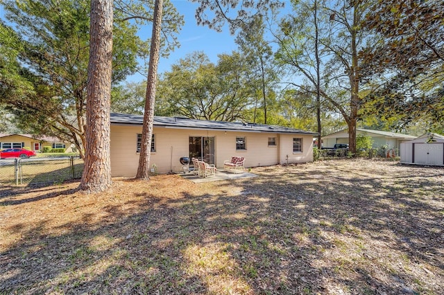 back of property with an outbuilding, fence, a patio, and a storage unit