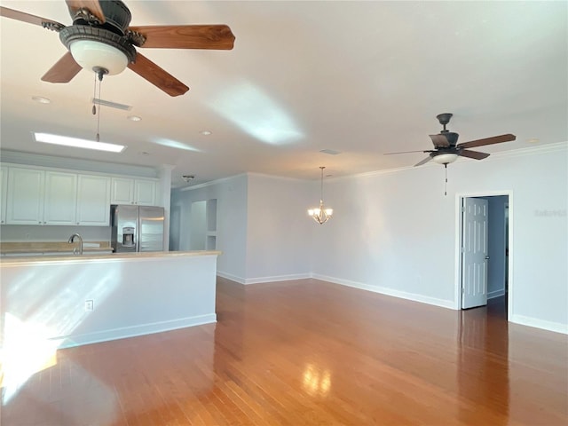 kitchen with crown molding, light countertops, dark wood-type flooring, white cabinets, and stainless steel fridge with ice dispenser