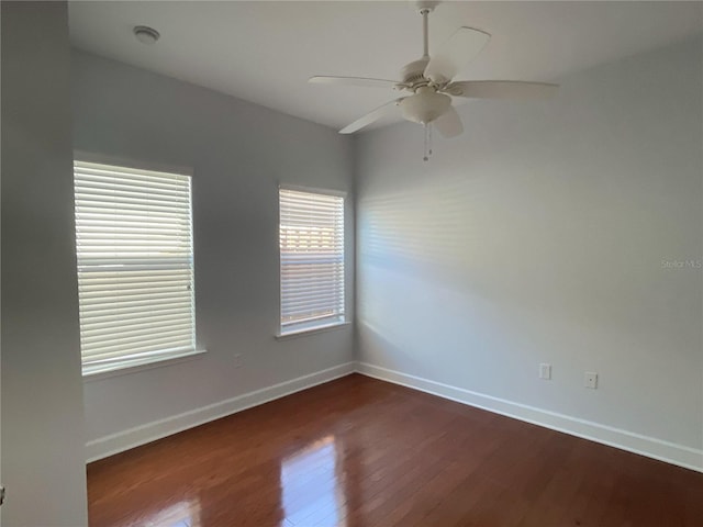 empty room with dark wood finished floors, baseboards, and ceiling fan