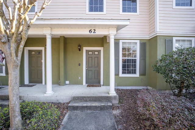 view of exterior entry featuring covered porch and stucco siding