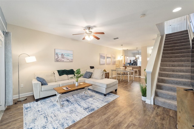 living room with baseboards, visible vents, ceiling fan, stairway, and wood finished floors