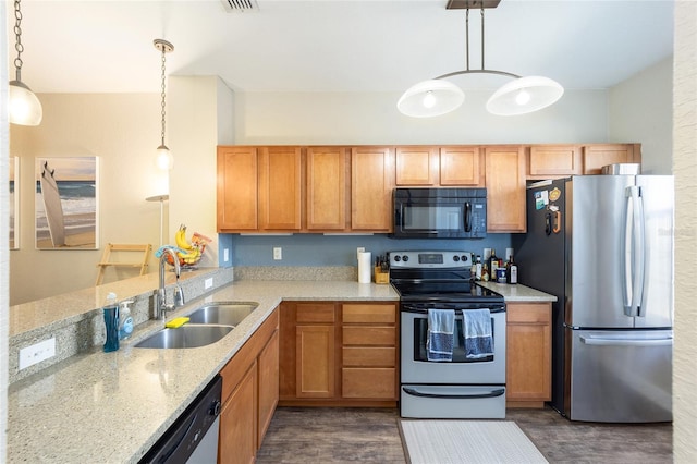 kitchen featuring stainless steel appliances, light stone counters, a sink, and decorative light fixtures