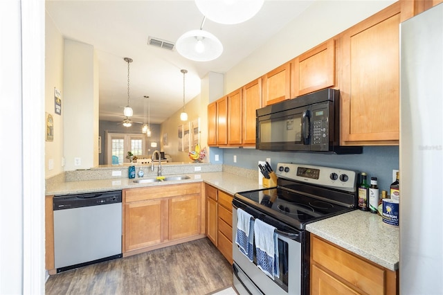 kitchen featuring pendant lighting, stainless steel appliances, visible vents, a sink, and wood finished floors