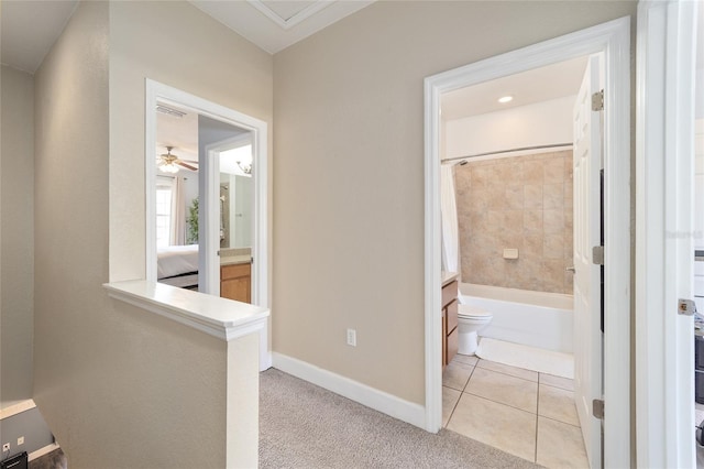 hallway with light carpet, baseboards, and light tile patterned floors