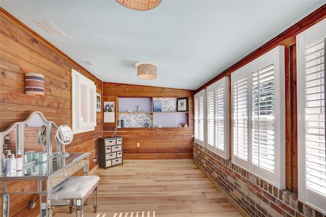 living area featuring brick wall, wooden walls, visible vents, and wood finished floors