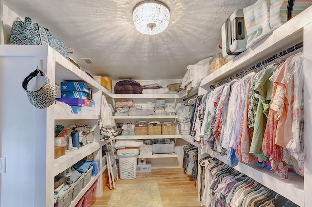 spacious closet featuring a chandelier, visible vents, and wood finished floors