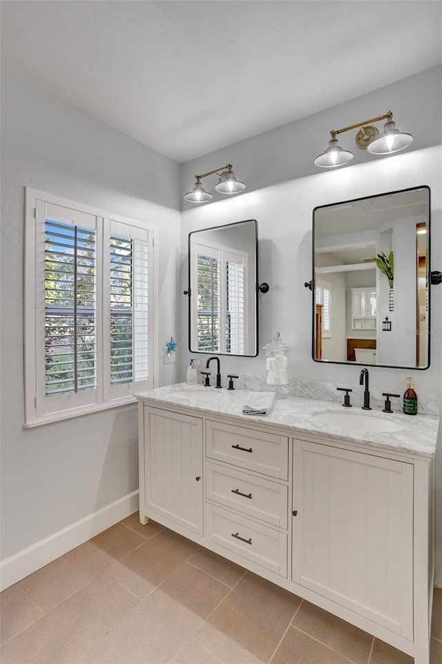 bathroom featuring baseboards, double vanity, a sink, and tile patterned floors