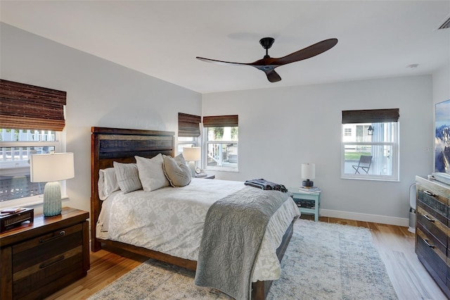 bedroom featuring a ceiling fan, light wood-style flooring, visible vents, and baseboards