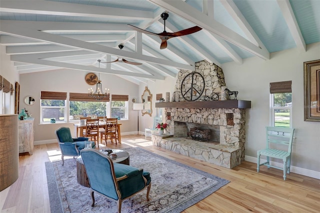 living room featuring ceiling fan with notable chandelier, a fireplace, beamed ceiling, and wood finished floors