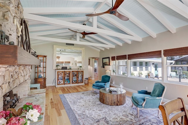 sunroom / solarium featuring lofted ceiling with beams, a fireplace, visible vents, and a ceiling fan