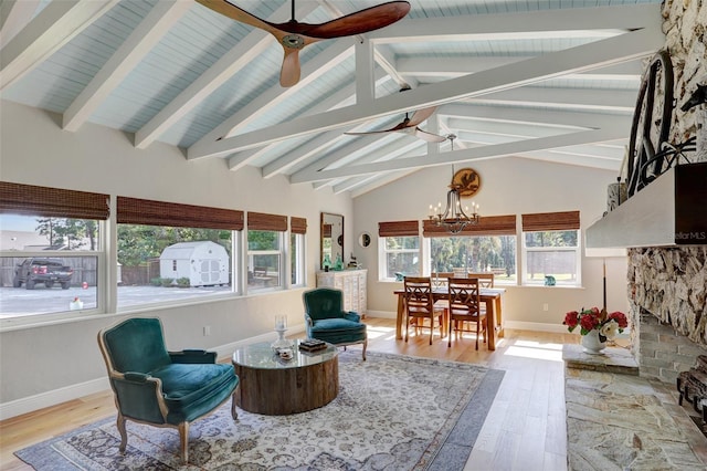 sunroom with vaulted ceiling with beams, ceiling fan with notable chandelier, and a fireplace