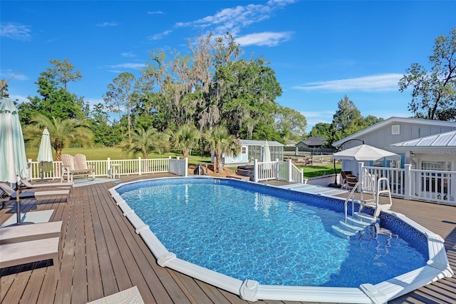 pool featuring an outdoor structure, a wooden deck, and fence