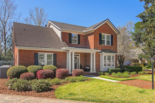 view of front of property with brick siding, central AC unit, a front yard, and fence