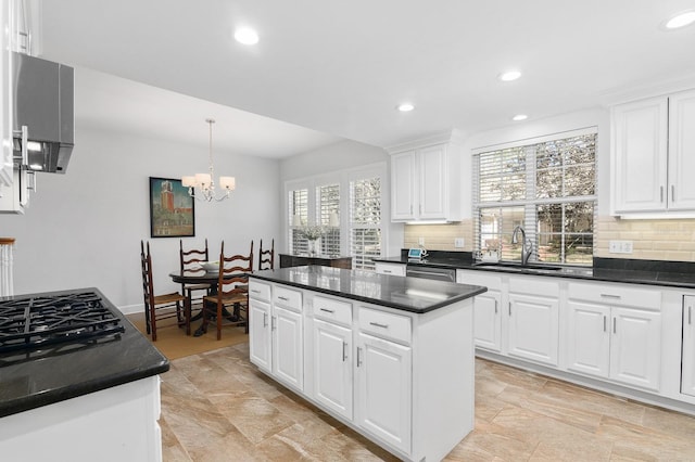 kitchen with dark countertops, a kitchen island, tasteful backsplash, and a sink