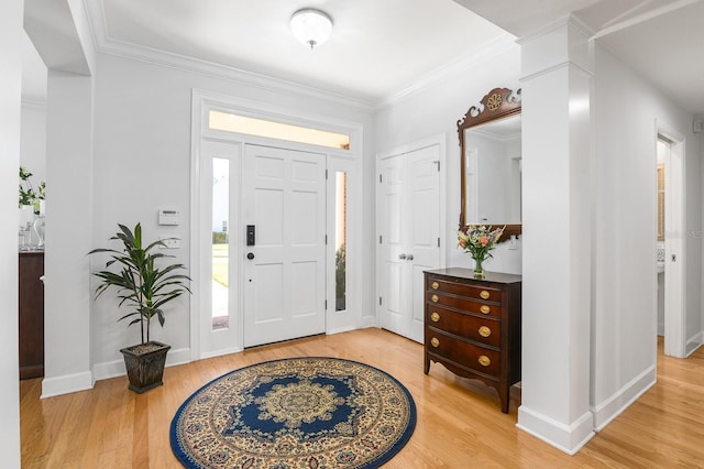 entrance foyer with decorative columns, light wood-style floors, baseboards, and ornamental molding