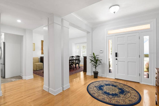 entrance foyer with light wood-type flooring, baseboards, ornamental molding, and decorative columns