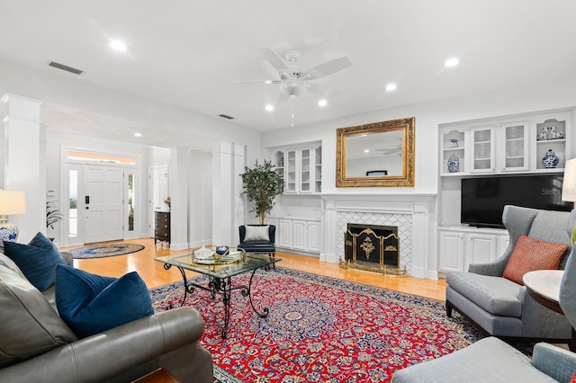 living room with a tiled fireplace, visible vents, light wood-style flooring, and recessed lighting