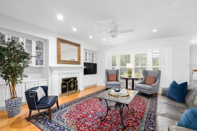 living area featuring built in features, recessed lighting, a fireplace, and light wood-type flooring