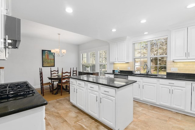 kitchen featuring dark countertops, backsplash, a kitchen island, and a sink