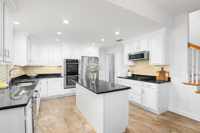 kitchen featuring visible vents, a kitchen island, dark countertops, appliances with stainless steel finishes, and white cabinets