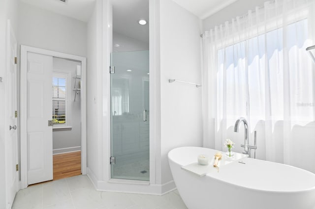 bathroom featuring marble finish floor, a stall shower, baseboards, and a freestanding tub