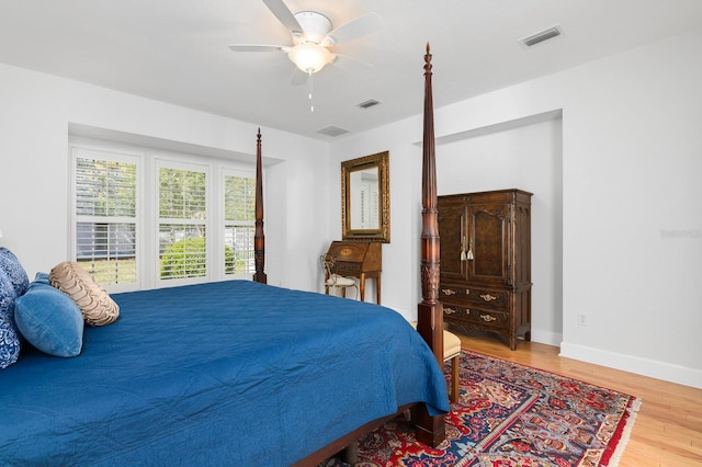 bedroom featuring ceiling fan, visible vents, baseboards, and wood finished floors