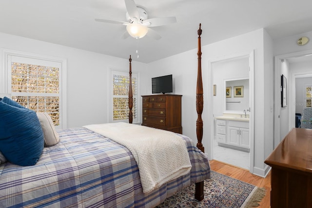 bedroom featuring light wood finished floors, connected bathroom, ceiling fan, and a sink