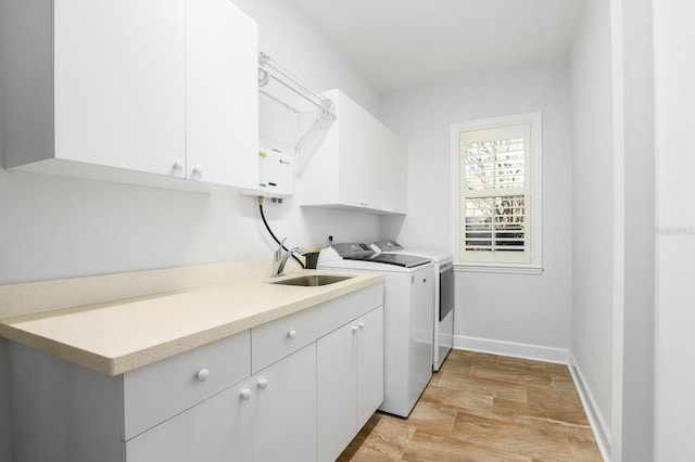 washroom with a sink, baseboards, cabinet space, and washer and clothes dryer